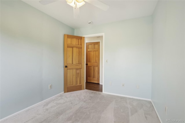carpeted empty room featuring ceiling fan and baseboards