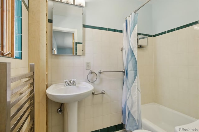 bathroom with tile walls and shower / bath combo with shower curtain