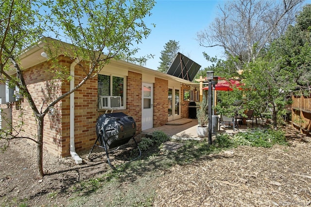back of property with brick siding, a patio area, fence, and cooling unit