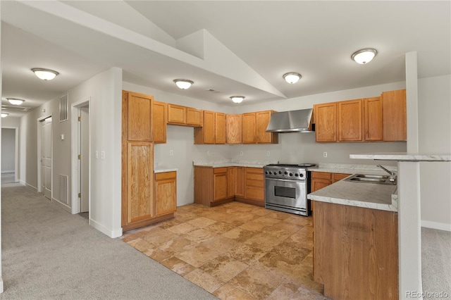 kitchen with lofted ceiling, sink, wall chimney exhaust hood, high end stove, and light colored carpet