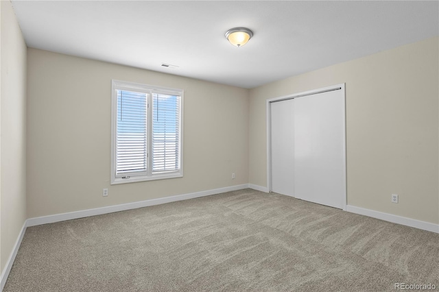 unfurnished bedroom with light carpet and a closet