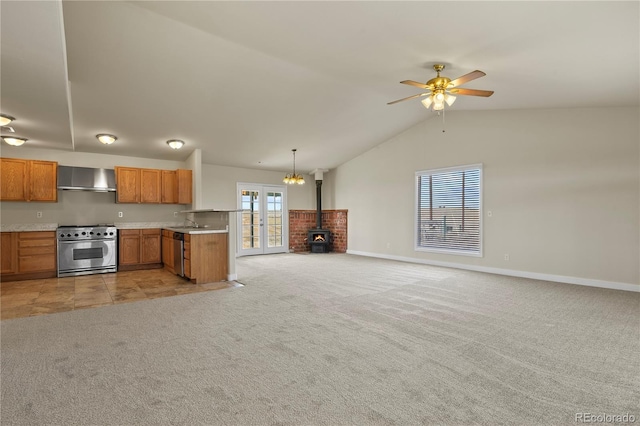 kitchen with hanging light fixtures, wall chimney exhaust hood, stainless steel appliances, ceiling fan with notable chandelier, and vaulted ceiling