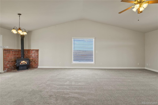 unfurnished living room featuring carpet floors, vaulted ceiling, ceiling fan, and a wood stove