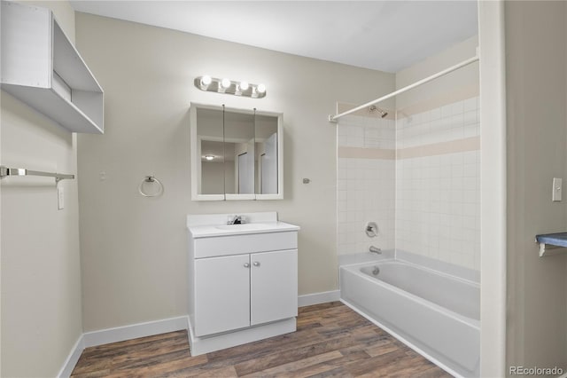 bathroom with hardwood / wood-style floors, tiled shower / bath combo, and vanity