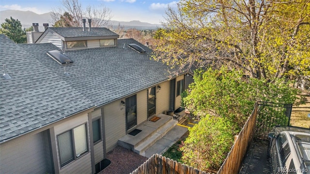 6447 Jonathan Ct, Colorado Springs, CO 80918 - rear view of property featuring a mountain view, fence, a shingled roof, and a chimney