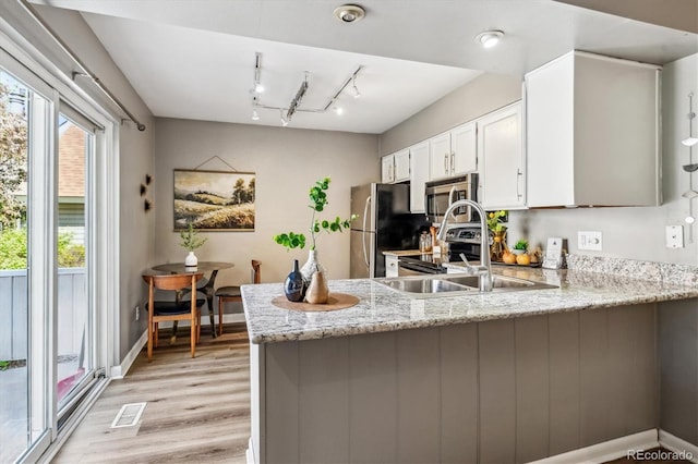 2491 S Xanadu Way Unit A, Aurora, CO 80014 - kitchen with stainless steel appliances, a peninsula, light wood-style floors, white cabinets, and light stone counters