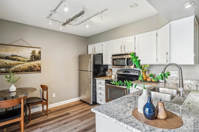 2491 S Xanadu Way Unit A, Aurora, CO 80014 - kitchen featuring stainless steel appliances, white cabinets, light wood-style floors, a sink, and baseboards