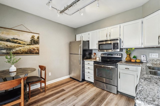 2491 S Xanadu Way Unit A, Aurora, CO 80014 - kitchen featuring stainless steel appliances, rail lighting, light wood-type flooring, white cabinets, and baseboards