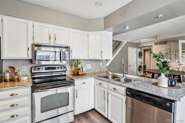 2491 S Xanadu Way Unit A, Aurora, CO 80014 - kitchen featuring appliances with stainless steel finishes, stacked washer / drying machine, a sink, a peninsula, and white cabinets