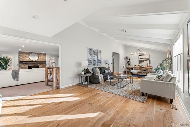 living room featuring an inviting chandelier, vaulted ceiling with beams, a fireplace, and wood-type flooring