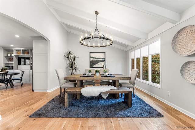 dining area featuring light hardwood / wood-style flooring, an inviting chandelier, and vaulted ceiling with beams