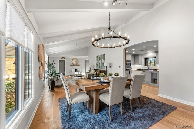 dining room featuring vaulted ceiling with beams, light hardwood / wood-style floors, and a notable chandelier