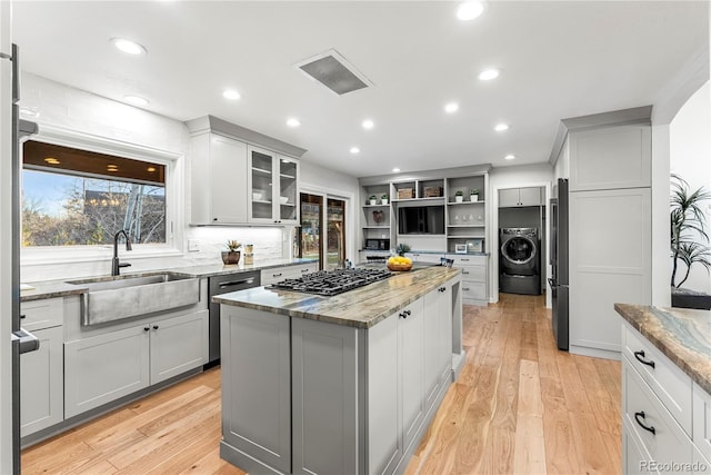 kitchen featuring light stone countertops, washer / dryer, sink, and a kitchen island