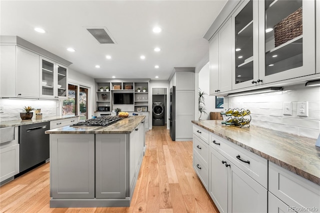 kitchen featuring a kitchen island, dishwashing machine, light stone counters, and light hardwood / wood-style flooring