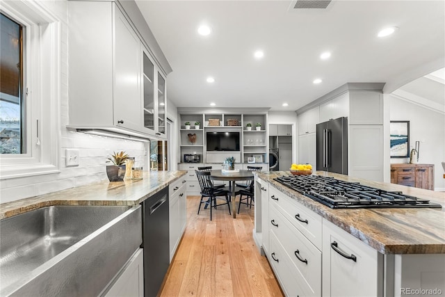 kitchen featuring stainless steel appliances, white cabinetry, light wood-type flooring, and light stone counters