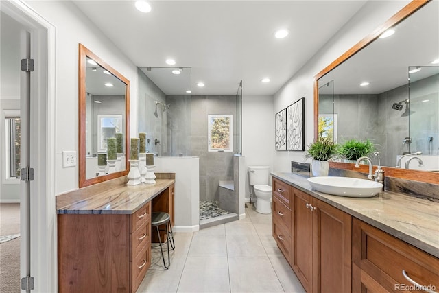 bathroom with a wealth of natural light, a tile shower, vanity, and toilet