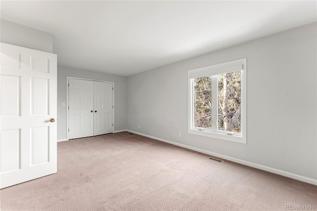 unfurnished bedroom with light colored carpet and a closet