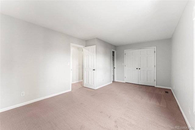 unfurnished bedroom with light colored carpet and a closet