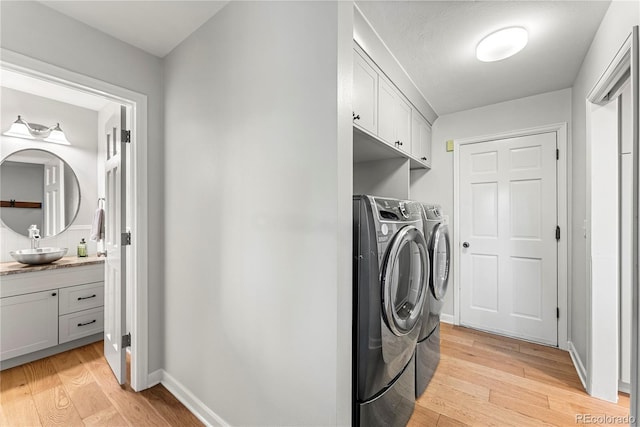 washroom featuring sink, cabinets, washer and clothes dryer, and light hardwood / wood-style floors