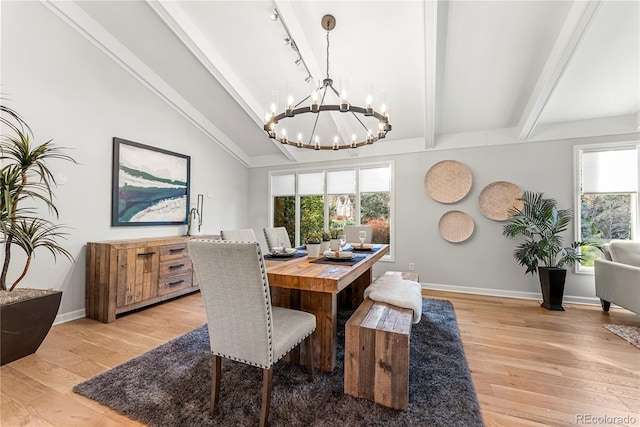 dining area featuring track lighting, lofted ceiling with beams, a chandelier, and light wood-type flooring