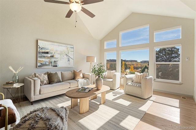 living room with light wood-type flooring, high vaulted ceiling, and ceiling fan