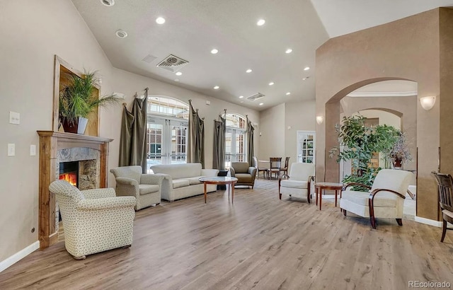 living area featuring recessed lighting, light wood-type flooring, high vaulted ceiling, baseboards, and arched walkways