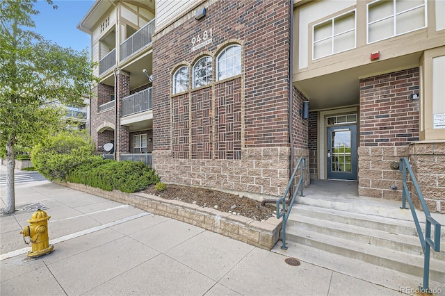 view of exterior entry featuring brick siding and stone siding