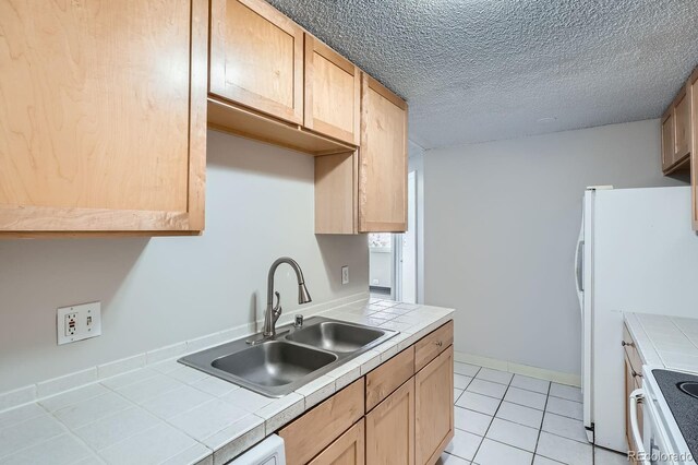 2225 Buchtel Blvd Unit 1003, Denver, CO 80210 - kitchen with a textured ceiling, light brown cabinetry, a sink, tile counters, and light tile patterned flooring