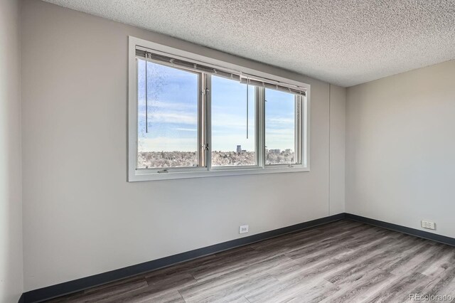 2225 Buchtel Blvd Unit 1003, Denver, CO 80210 - unfurnished room featuring plenty of natural light, baseboards, a textured ceiling, and wood finished floors
