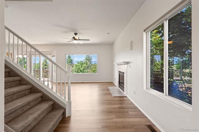4839 Spotted Horse Dr, Colorado Springs, CO 80923 - unfurnished living room featuring wood finished floors, a ceiling fan, stairway, and a fireplace with flush hearth