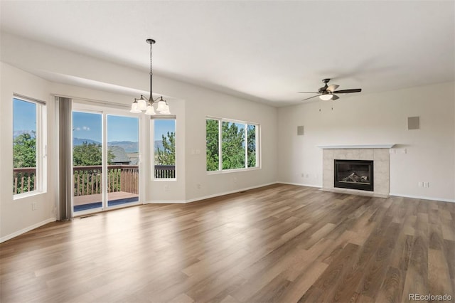 4839 Spotted Horse Dr, Colorado Springs, CO 80923 - unfurnished living room featuring a ceiling fan, wood finished floors, a chandelier, and a fireplace