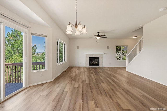 4839 Spotted Horse Dr, Colorado Springs, CO 80923 - unfurnished living room featuring light wood-style flooring, ceiling fan, a chandelier, a fireplace, and stairs