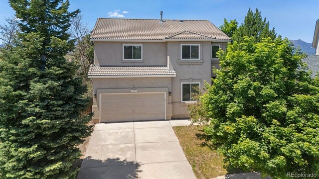 4839 Spotted Horse Dr, Colorado Springs, CO 80923 - view of front of house featuring a tile roof, an attached garage, driveway, and stucco siding