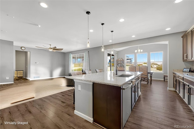 kitchen with ceiling fan with notable chandelier, sink, a center island with sink, dark hardwood / wood-style floors, and hanging light fixtures