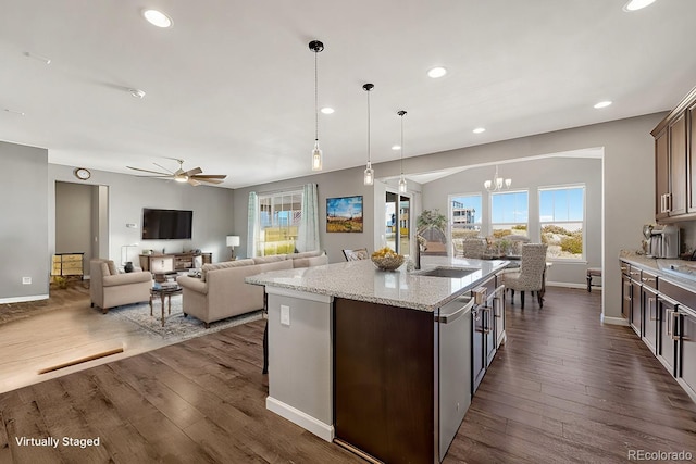 kitchen with sink, hanging light fixtures, a kitchen island with sink, dark brown cabinets, and ceiling fan with notable chandelier