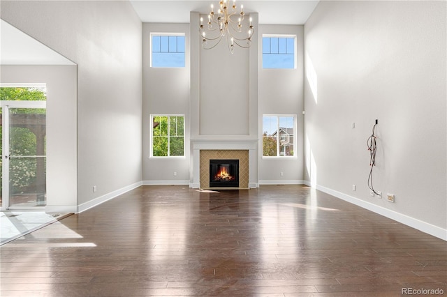 23870 E Dorado Pl, Aurora, CO 80016 - unfurnished living room featuring dark wood-style floors, a towering ceiling, a chandelier, and healthy amount of natural light