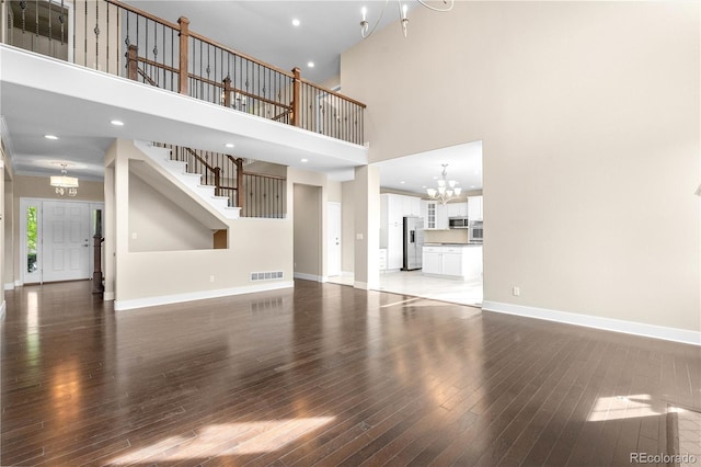 23870 E Dorado Pl, Aurora, CO 80016 - unfurnished living room with a chandelier, a towering ceiling, wood-type flooring, baseboards, and recessed lighting