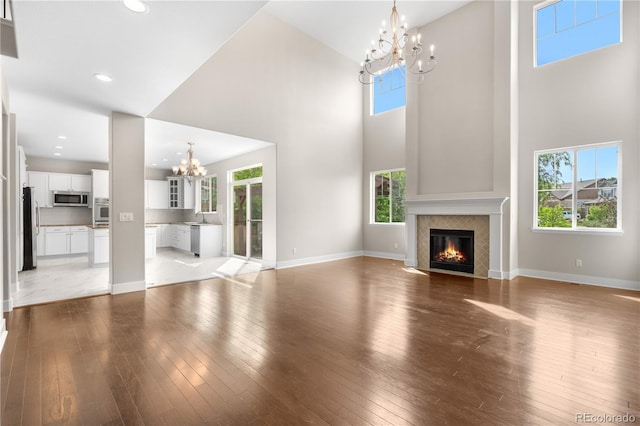 23870 E Dorado Pl, Aurora, CO 80016 - unfurnished living room with a chandelier, a fireplace with flush hearth, light wood-type flooring, a high ceiling, and a sink