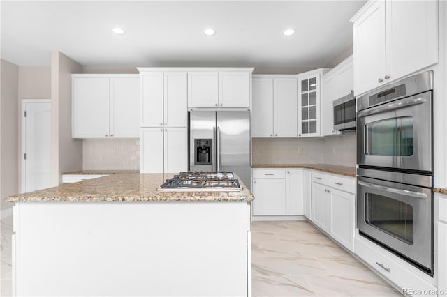 23870 E Dorado Pl, Aurora, CO 80016 - kitchen featuring appliances with stainless steel finishes, light marble finish floors, a center island, recessed lighting, and light stone countertops