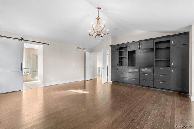 23870 E Dorado Pl, Aurora, CO 80016 - unfurnished living room featuring dark wood-style flooring, a barn door, a chandelier, vaulted ceiling, and wainscoting