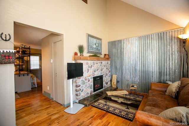 living room with high vaulted ceiling, visible vents, wood finished floors, and a stone fireplace