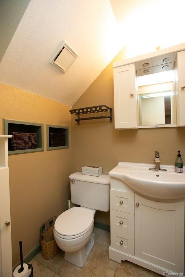 bathroom featuring baseboards, lofted ceiling, toilet, tile patterned flooring, and vanity