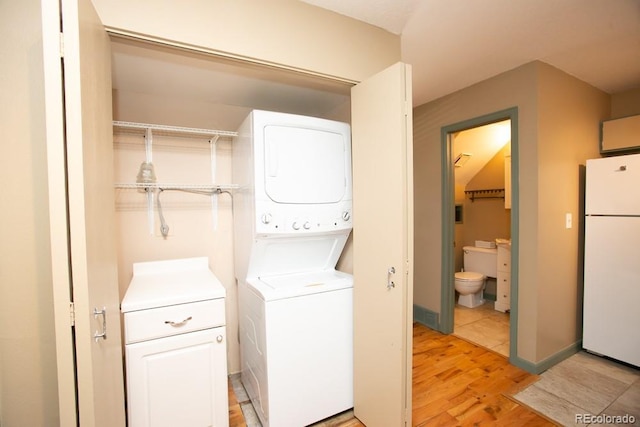 laundry area featuring laundry area, stacked washing maching and dryer, and light wood-style floors