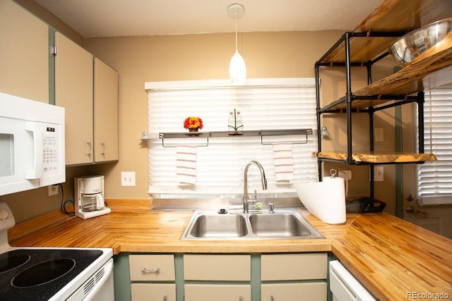 kitchen with white appliances, decorative light fixtures, a sink, and wood counters