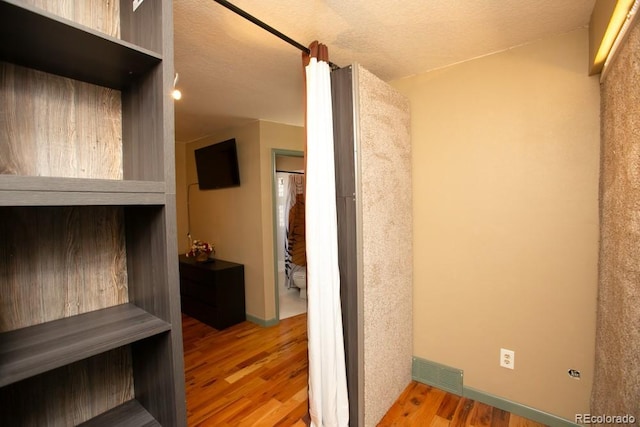 interior space with a textured ceiling, wood finished floors, visible vents, and baseboards