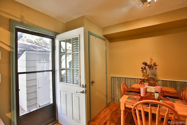 doorway with a wainscoted wall and wood finished floors