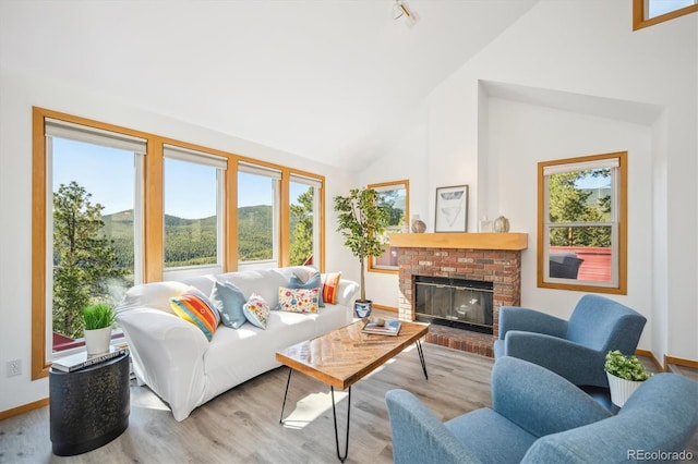 7350 Timber Trail Rd, Evergreen, CO 80439 - living room featuring wood finished floors, baseboards, high vaulted ceiling, and a brick fireplace