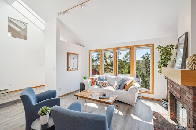 7350 Timber Trail Rd, Evergreen, CO 80439 - living room with rail lighting, baseboards, a brick fireplace, high vaulted ceiling, and light wood-style floors