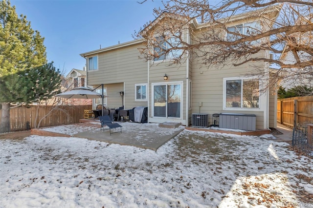 snow covered house with central AC unit and a patio