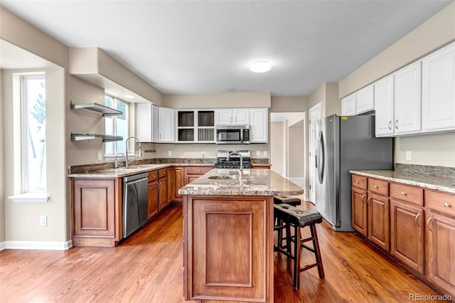 12047 W Coal Mine Dr, Littleton, CO 80127 - kitchen featuring light stone counters, a sink, open shelves, a kitchen breakfast bar, and stainless steel appliances